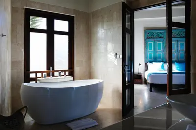 a bathroom with a tub and a bedroom with a bed at Umah Daun by Nakula in Canggu