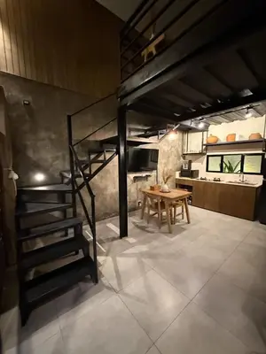 a kitchen with a staircase and a table in a room at Ambara Villa - Quiet Luxury in Umalas in Canggu