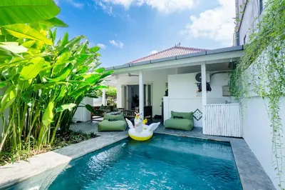 a swimming pool in front of a house with a pool toy at The White House Villa Taeyvela Seminyak in Seminyak