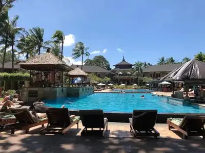 a large swimming pool with chairs and people in it at Classic Balinese Stay Jayakarta - 5 min walk to Kuta beach AC WiFi ! in Kuta