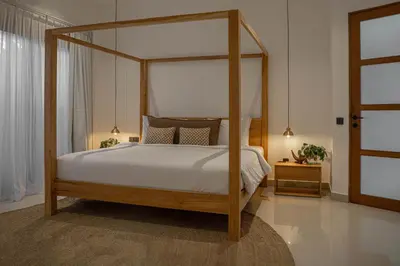 a bedroom with a canopy bed with white sheets and pillows at Villa Under the Sun - Seminyak in Seminyak