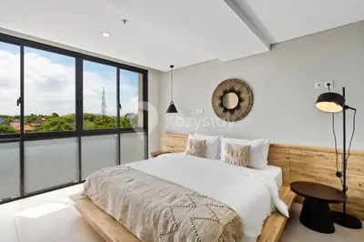 a bedroom with a bed and a large window at Sariha by Kozystay - Nusa Dua in Nusa Dua