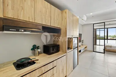 a kitchen with wooden cabinets and a counter top at Sariha by Kozystay - Nusa Dua in Nusa Dua