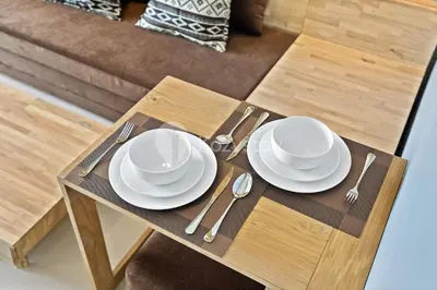 a table with white plates and silverware on it at Sariha by Kozystay - Nusa Dua in Nusa Dua