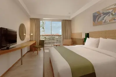 a hotel room with a large bed and a television at Diamond Hotel Kuta Bali in Kuta
