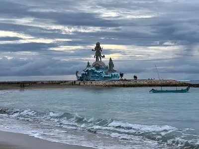 a statue on a beach next to the ocean at Easton Homestay in Ngurah Rai International Airport