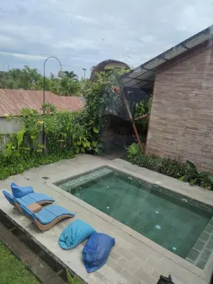 a swimming pool with two lounge chairs next to a house at Bashania in Kerobokan