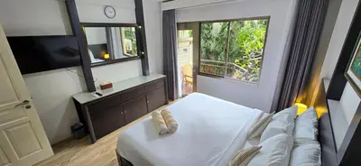 a bedroom with a white bed and a television at The Palmana Tropical Courtyard Jayakarta Residence 12 in Seminyak