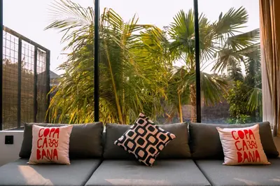 a couch with pillows on it in a room with palm trees at Casa Ipanema, Luxury 2 Bedrooms Villa with Cinema in Private Quiet Area in Canggu