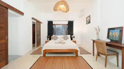 a bedroom with a bed and a desk at Villa Mogi by Villa Finder in Seminyak