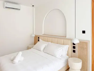 a white bedroom with a white bed and a window at Anjou - Twin Villa in Berawa Canggu in Canggu