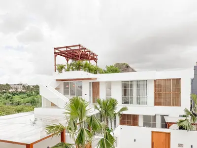 a white house with palm trees in front of it at Anjou - Twin Villa in Berawa Canggu in Canggu
