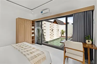 a bedroom with a bed and a desk and a window at Navaya Villa by Kozystay - Seminyak in Seminyak