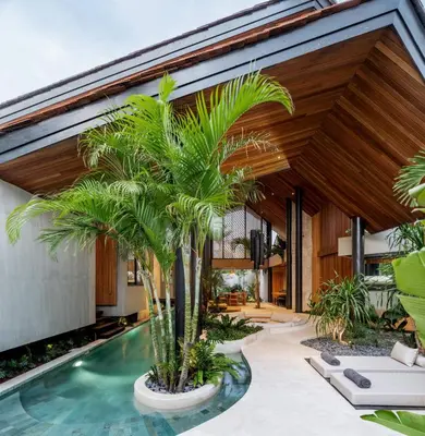 an indoor pool with palm trees in front of a house at House of Winds Complex - Stylish 12BR Design Estate - 4 Villas near Canggu in Kerobokan