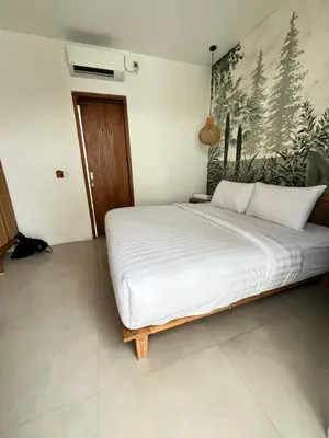 a bedroom with a white bed with a painting on the wall at Phil's Harmony Seminyak in Kerobokan