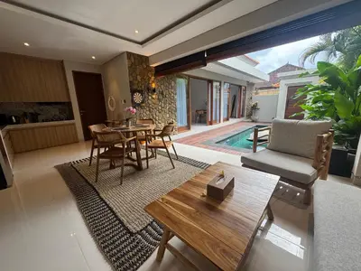 a living room with a table and chairs and a pool at Villa Elysia in Canggu