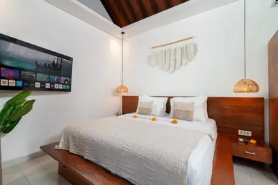 a bedroom with a bed and a tv on the wall at Villa Kunti in Seminyak