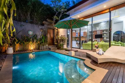 an outdoor swimming pool with a patio and a house at Villa Yudhistira by JB Villas in Seminyak