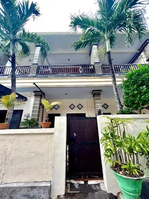 a house with a black gate and palm trees at OSA Guest House 3 in Seminyak