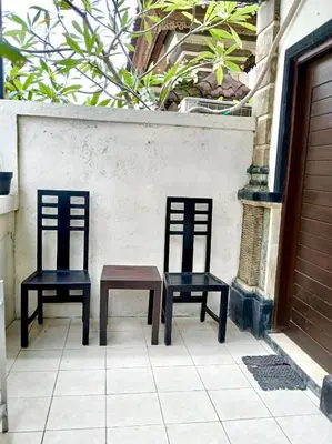 two chairs and a table sitting next to a wall at OSA Guest House 3 in Seminyak