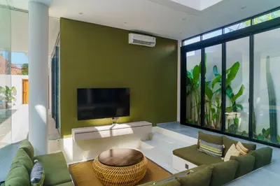 a living room with a green wall with a tv at New 3 Bedroom Villa with rooftop central Seminyak in Seminyak