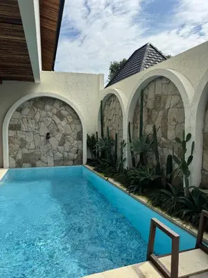 a swimming pool in a house with a stone wall at Tuluscoliving Villa Kuta 1, 4 Bedroom & 5 Bathroom in Ngurah Rai International Airport