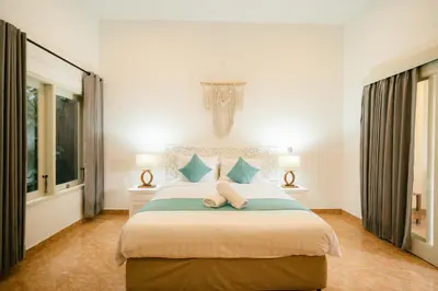 a bedroom with a large bed with blue pillows at Villa Nagomi in Seminyak