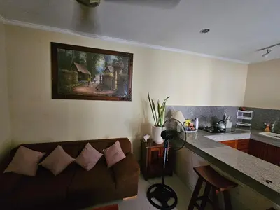 a living room with a couch and a painting on the wall at Cempaka Apartment Surfaris Inn in Legian