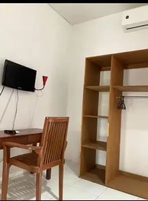 a desk with a chair and a television on a wall at RBE Hotel Kuta- 5 Min to Airport&Beach by Micky Studio in Ngurah Rai International Airport