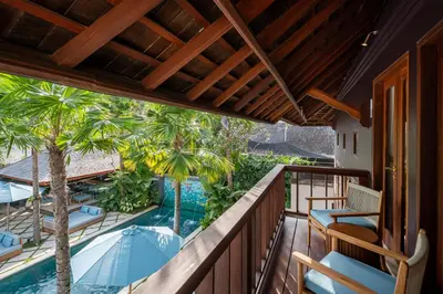 an outdoor balcony with chairs and a swimming pool at The Suaka Baliaga by Puri Asia in Seminyak