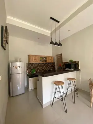 a kitchen with a refrigerator and two bar stools at Two spacious bedroom villa in Seminyak