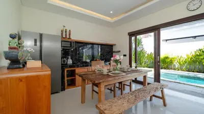a dining room with a wooden table and a large window at Villa Lange 3 by Villa Finder in Seminyak