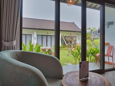 a living room with a couch and a table with a view of a yard at Mistral Studio Umalas in Canggu