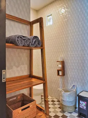 a bathroom with a toilet and a shelf with towels at Mistral Studio Umalas in Canggu
