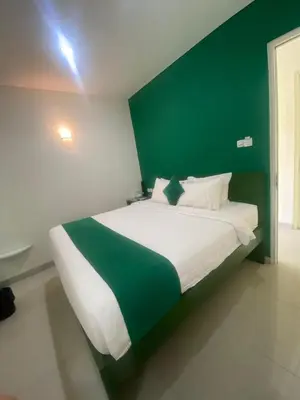 a bedroom with a large bed with a green wall at AI Hotel Kuta - 15 Second to the Beach and 1 Minute to Airport by Micky Studio in Ngurah Rai International Airport