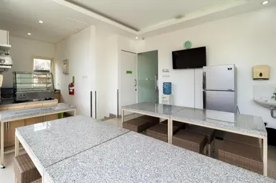 a kitchen with two tables and a refrigerator at AI Hotel Kuta - 15 Second to the Beach and 1 Minute to Airport by Micky Studio in Ngurah Rai International Airport