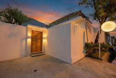 a white house with a front porch at dusk at Arvi Villa Pandawa Legian in Legian