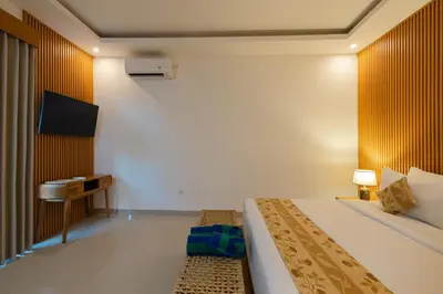 a hotel room with a bed and a tv at Arvi Villa Pandawa Legian in Legian