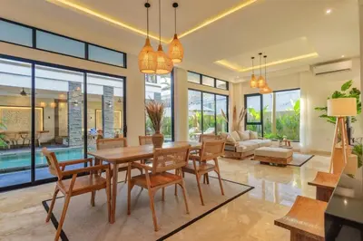 a dining room with a table and chairs and a couch at Villa Club Residence 8 by Maheswara in Canggu