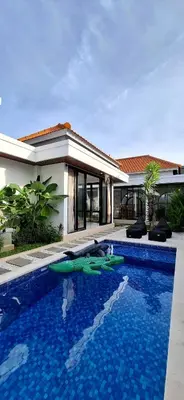 a villa with a swimming pool in front of a house at Modern Tropical 2 Bedroom Villa Ocean Nest in Canggu
