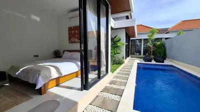 a bedroom with a bed and a swimming pool at Modern Tropical 2 Bedroom Villa Ocean Nest in Canggu