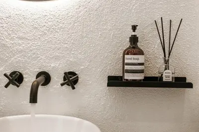 a bottle of alcohol sitting on a shelf next to a sink at All-White Villa with Pool, Sauna, Firepit & Office in Jimbaran