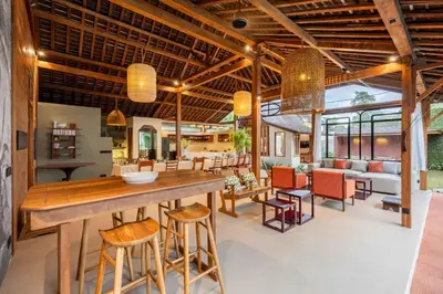 an open kitchen and living room with a bar and chairs at Villa Camini - Newly Renovated Beautiful 2BR Family Villa 6px With Garden And Private Pool in Kerobokan