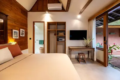 a bedroom with a bed and a desk and a television at Villa Camini - Newly Renovated Beautiful 2BR Family Villa 6px With Garden And Private Pool in Kerobokan