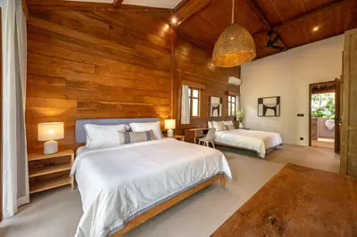 a bedroom with two beds and a wooden wall at Villa Camini - Newly Renovated Beautiful 2BR Family Villa 6px With Garden And Private Pool in Kerobokan