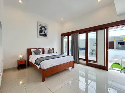 a bedroom with a large bed and a balcony at Mango Villa Seminyak in Kerobokan