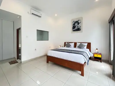 a bedroom with a bed and a tv on the wall at Mango Villa Seminyak in Kerobokan
