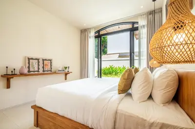 a bedroom with a large bed with a large window at Kuta Beach Villas by Great Bali Villas in Badung