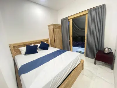 a bedroom with a bed with blue pillows and a window at SH Hotel Kuta- 20 Second to the Beach by Micky Studio in Legian