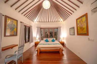 a bedroom with a bed and a chair in a room at The Sundara Room in Kerobokan